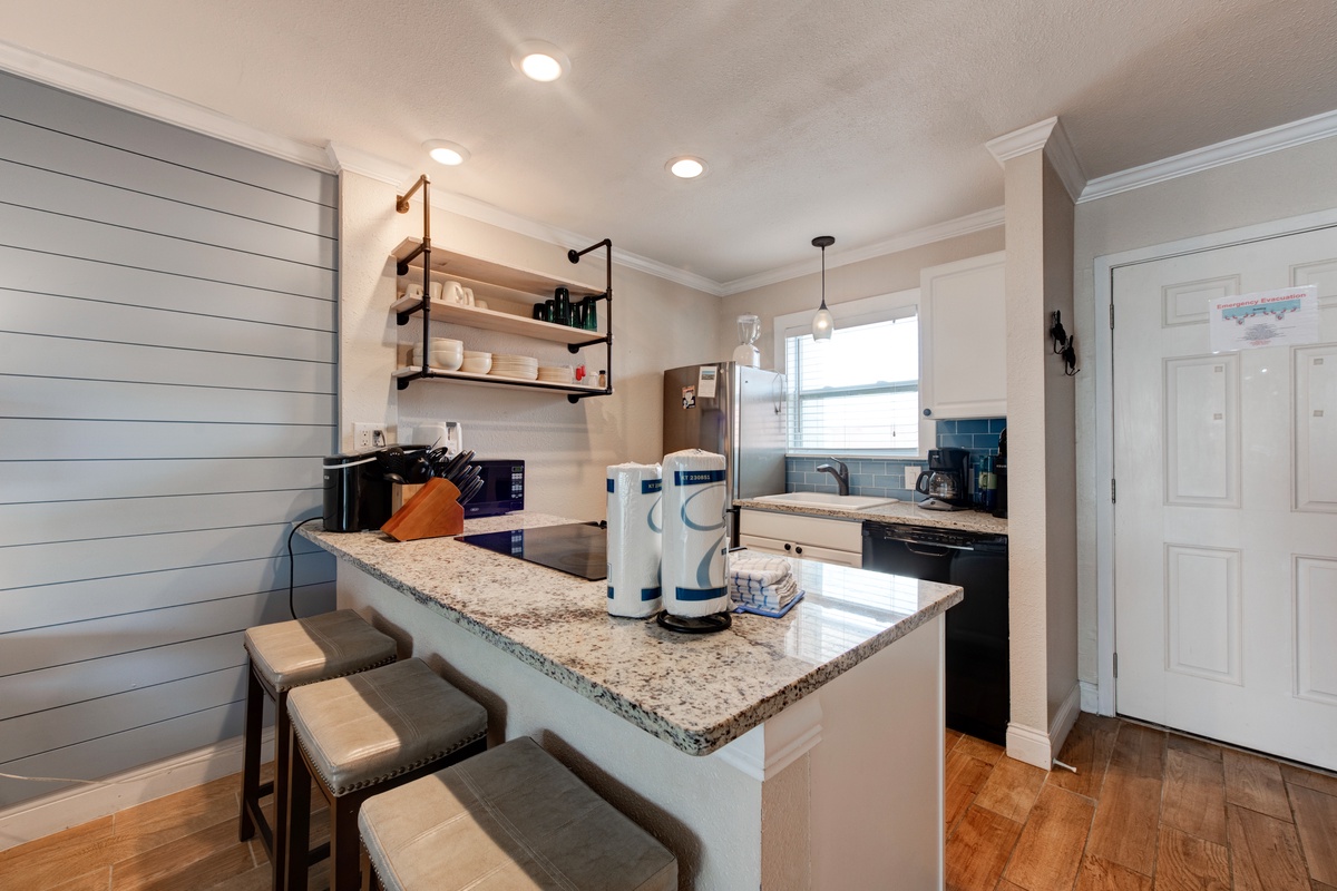 Gather around the granite island for coffee and conversation in your fully-equipped kitchen with modern appliances and charming open shelving.
