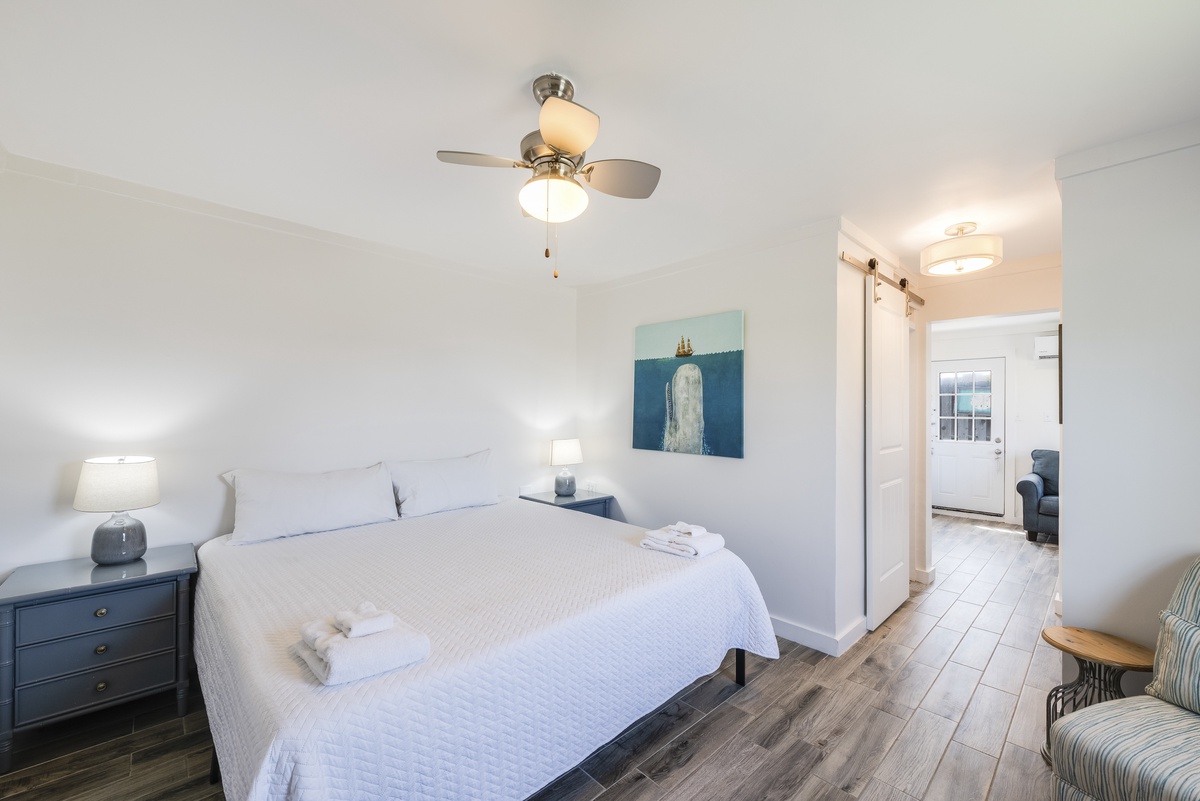 Wake up refreshed in this bright, coastal-inspired bedroom featuring a comfortable king bed, soft lighting, and a peaceful atmosphere.