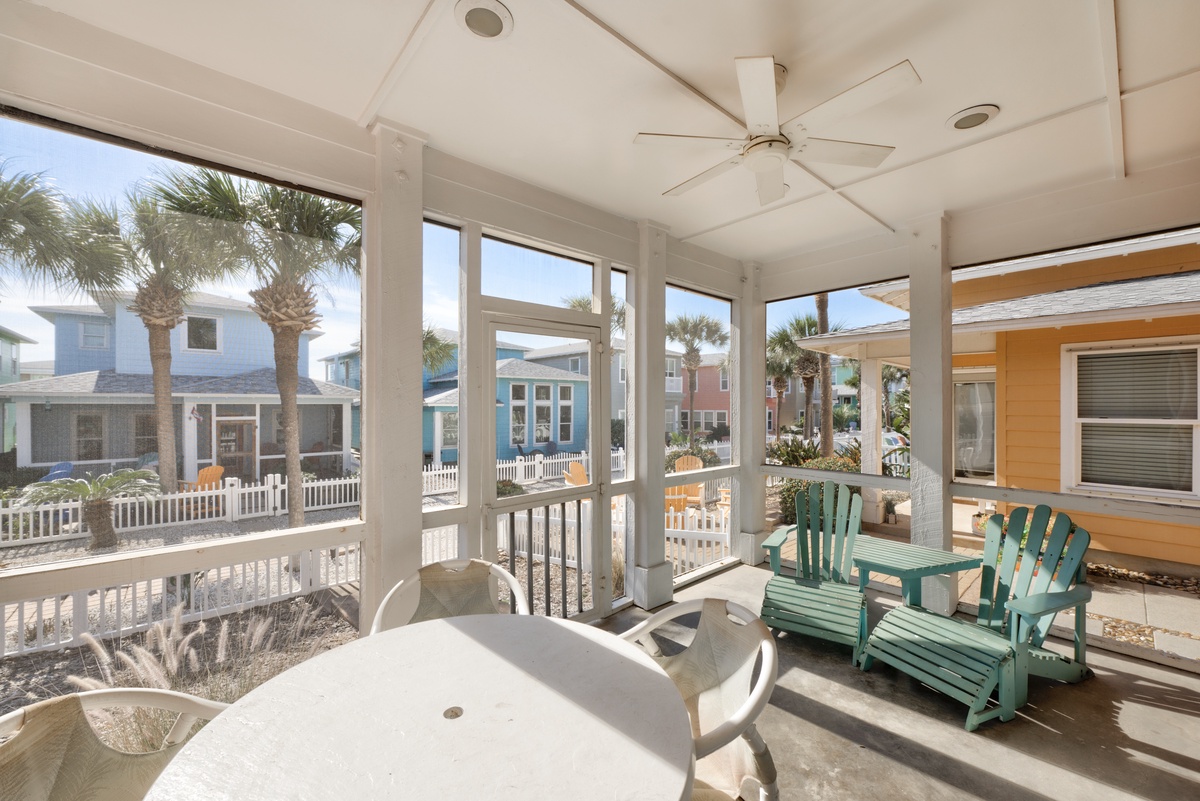 Relax on your screened porch with turquoise chairs and dining table, enjoying gentle ceiling fan breezes and tropical palm views.