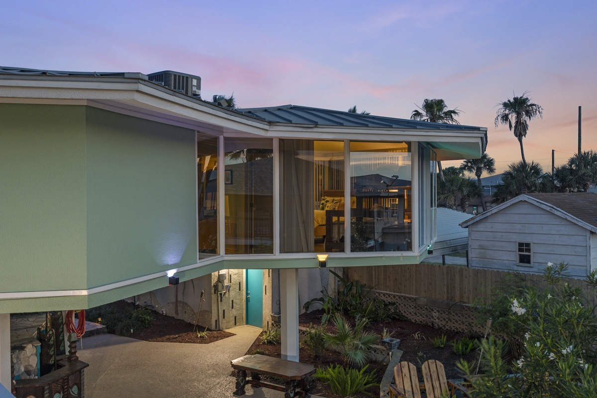 Modern beachside retreat with panoramic windows showcasing tropical surroundings and stunning twilight skies.