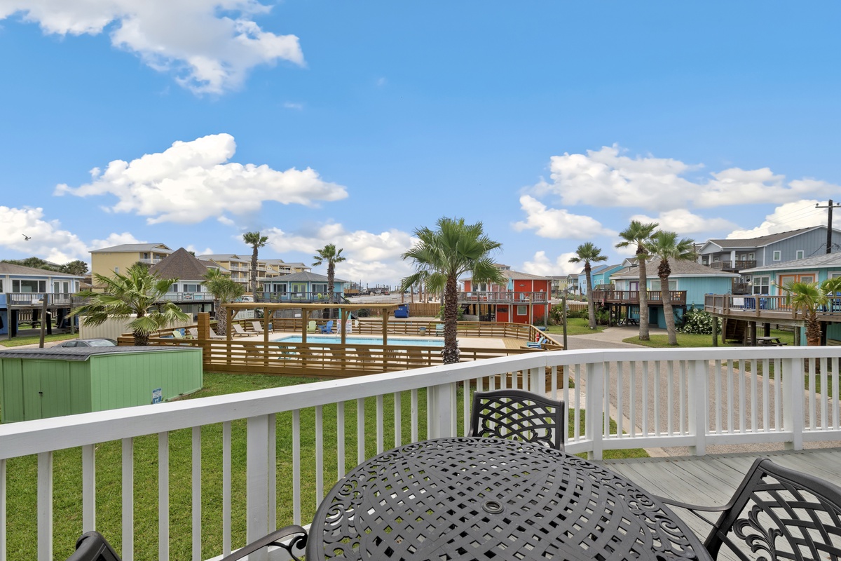 Coastal community featuring colorful beach houses and elevated properties surrounding a central recreational area with palm trees.