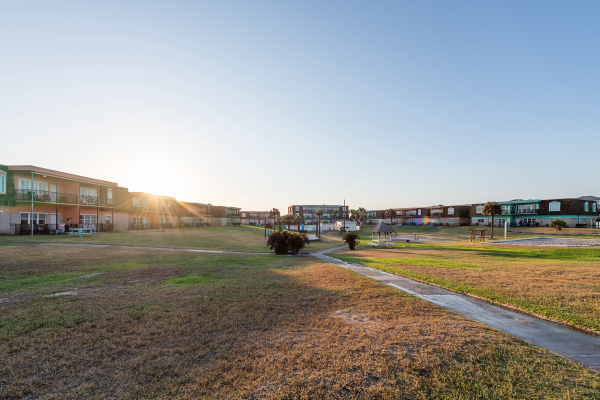 Golden sunrise illuminates this peaceful property complex with spacious grounds and well-maintained pathways connecting colorful buildings.
