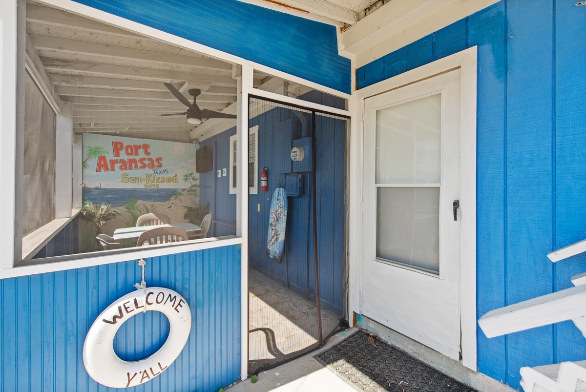Bright blue coastal cabin entrance welcomes you with charming nautical touches and Port Aransas artwork.