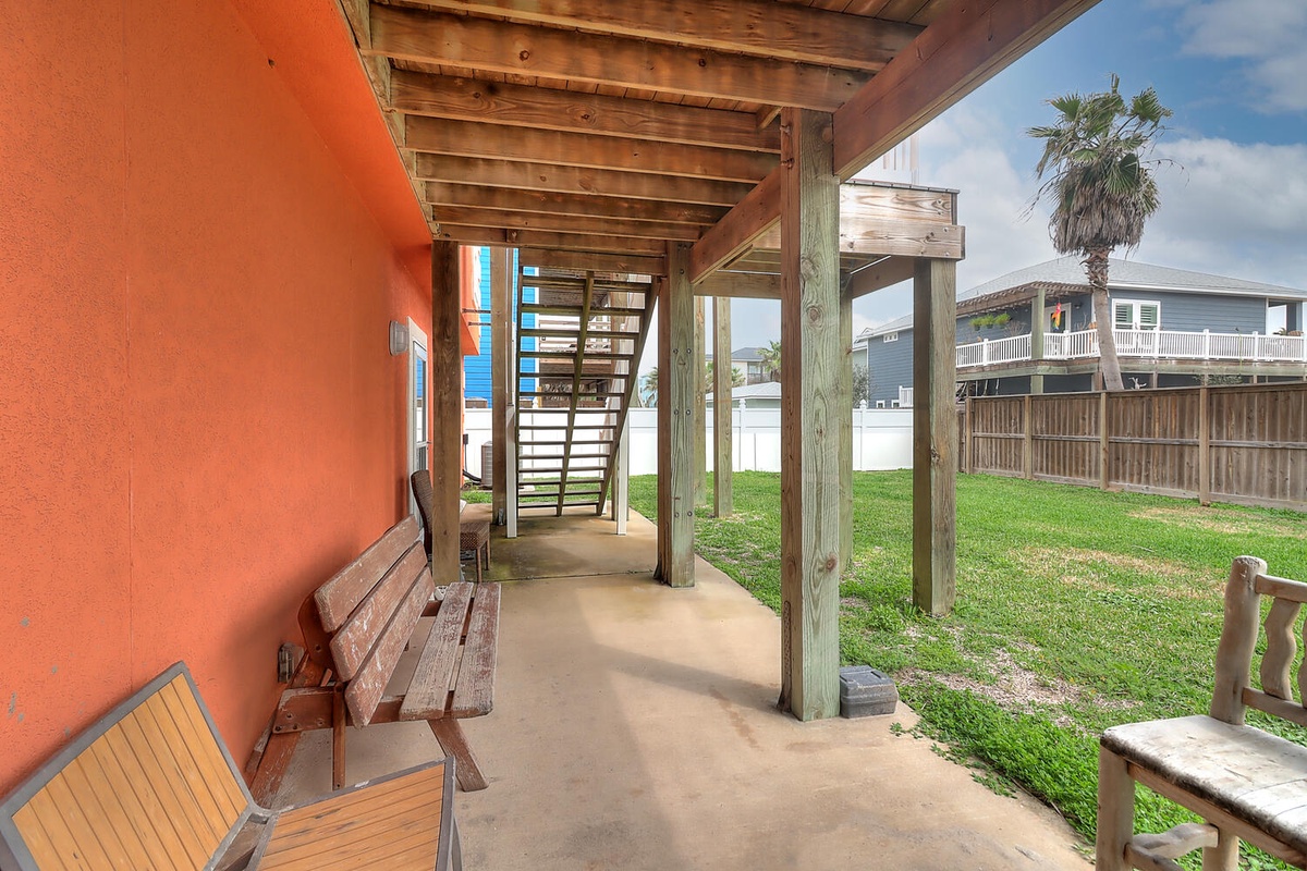 Relax on your covered patio with wooden seating and enjoy views of the green yard and neighboring coastal homes.