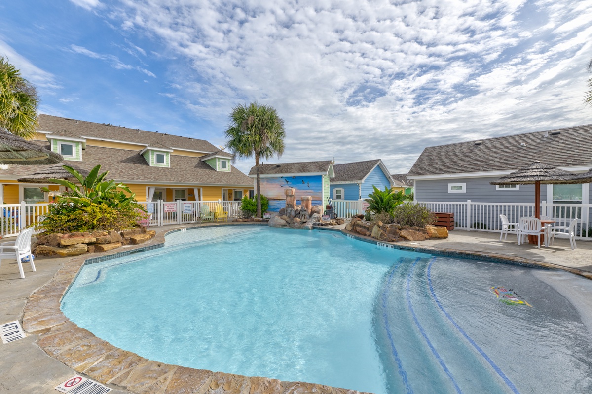 Your private oasis awaits with a sparkling pool surrounded by tropical landscaping and colorful beach cottages.