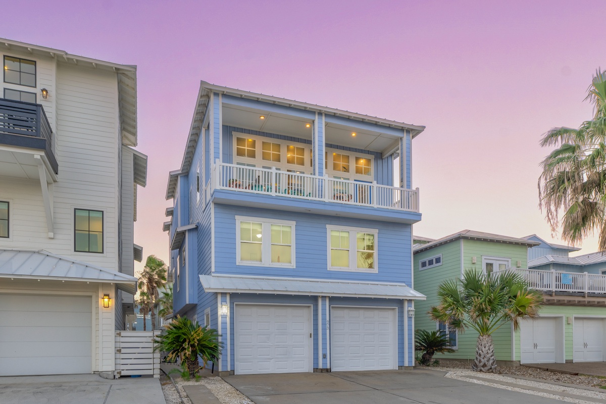 Charming blue beach house with covered balcony and tropical landscaping creates the perfect coastal retreat setting.