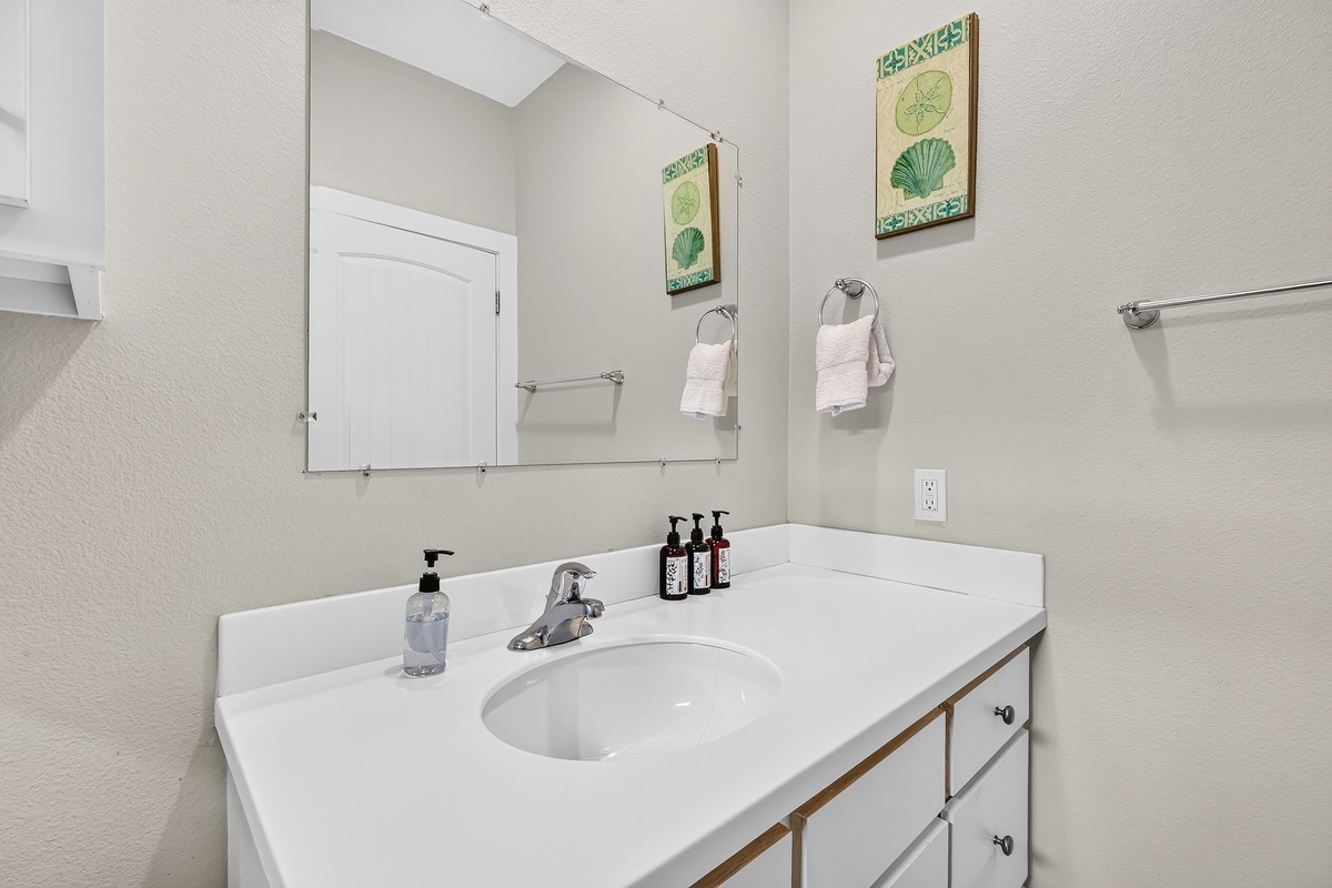 Bright shared bathroom featuring a spacious vanity and convenient storage.