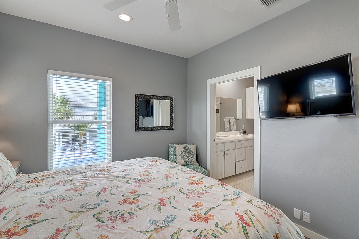 Relax in your bright bedroom with floral bedding, flat-screen TV, and private bathroom access for ultimate comfort.