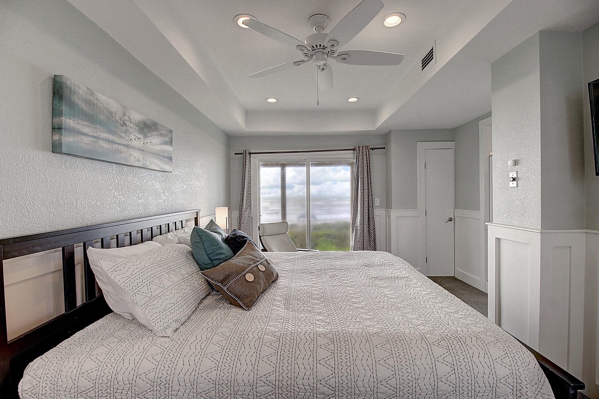 Unwind in your peaceful bedroom with soft linens, ceiling fan, and natural light streaming through the windows.