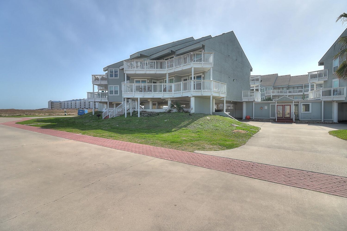 Beachfront property buildings with multiple balconies and parking areas in a coastal resort community.