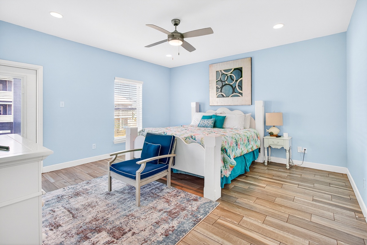 Drift off to peaceful sleep in your serene bedroom featuring soft blue walls, comfortable bedding, and a ceiling fan for perfect comfort.