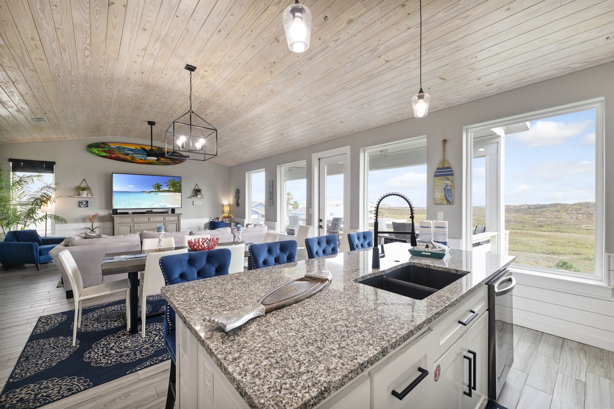 Your kitchen island opens to bright dining and living spaces, where natural light flows through expansive windows showcasing beautiful landscape views.