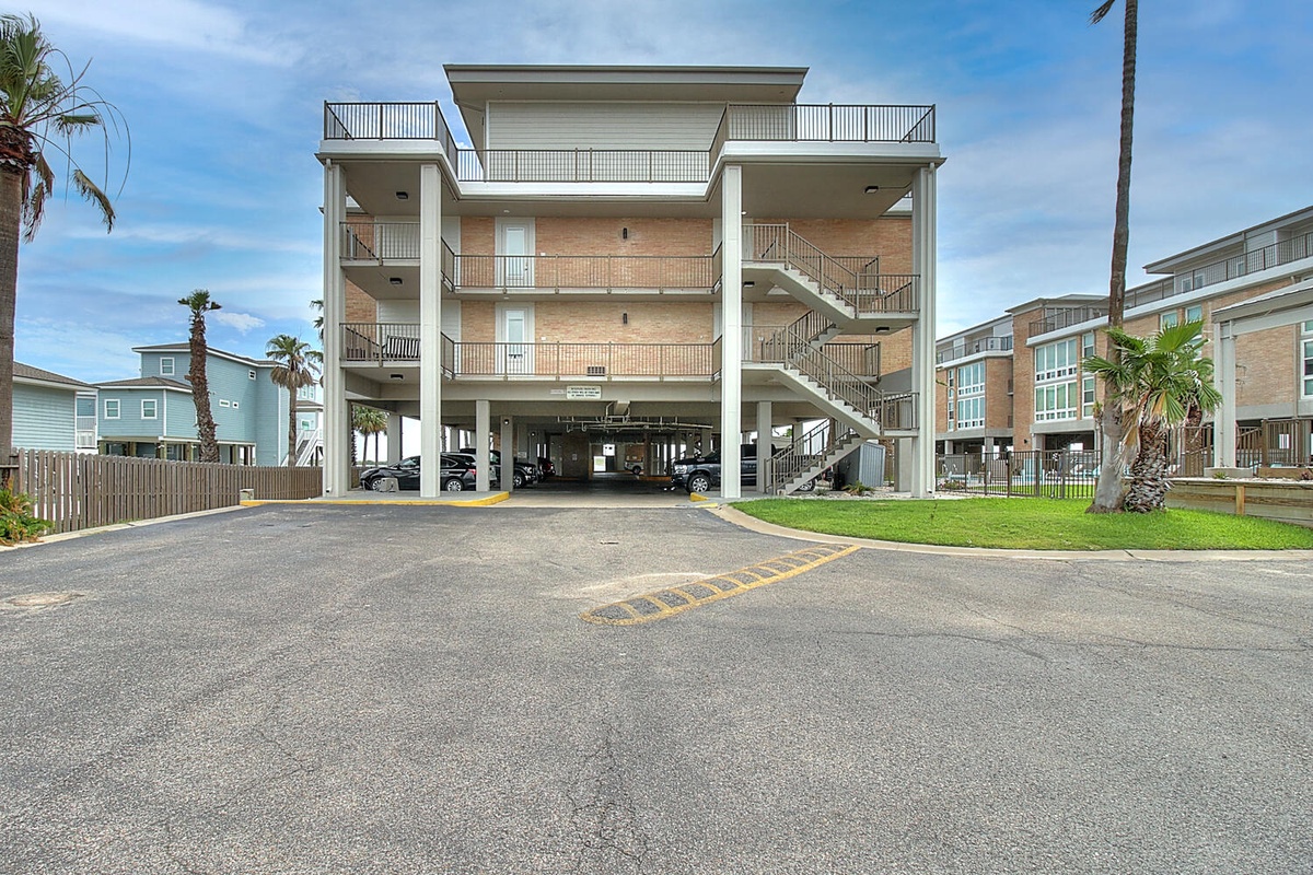 Modern beachside building with convenient covered parking and multiple balconies in a tropical coastal neighborhood.