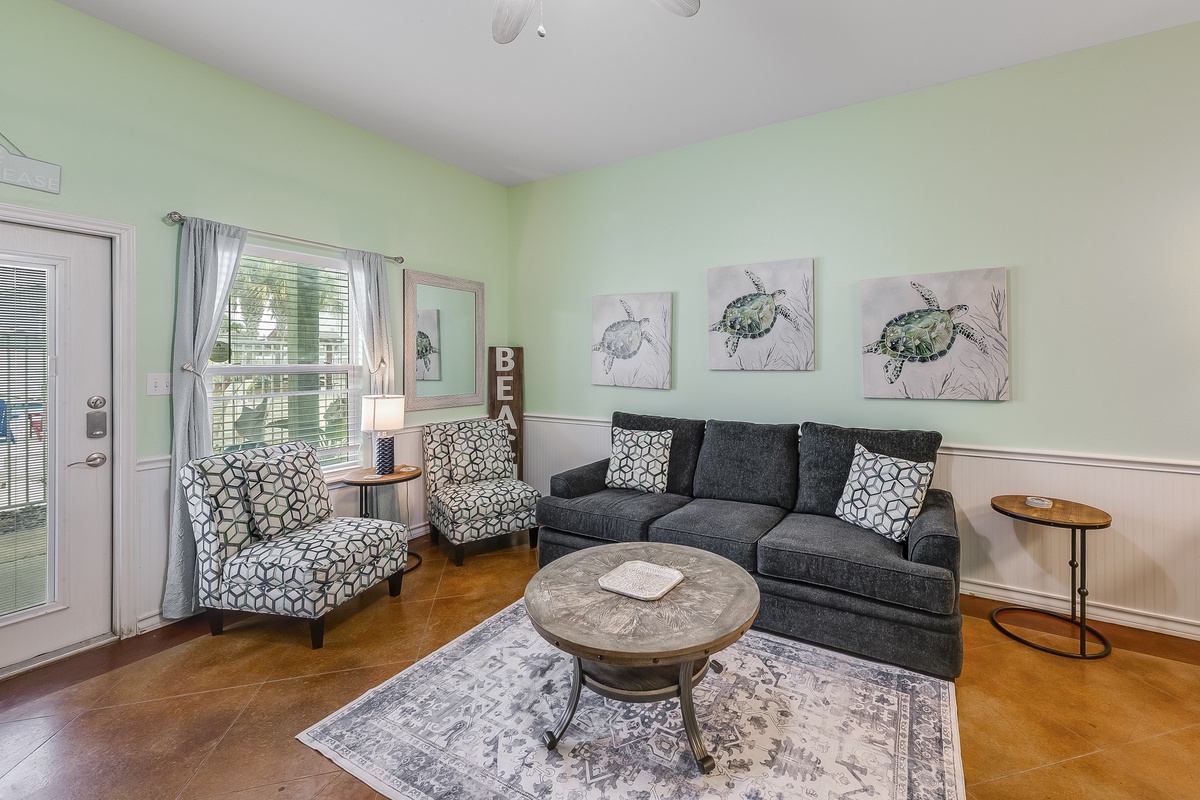 Relax in your coastal-themed living room with plush seating, turtle artwork, and peaceful mint green walls creating a serene beach house atmosphere.