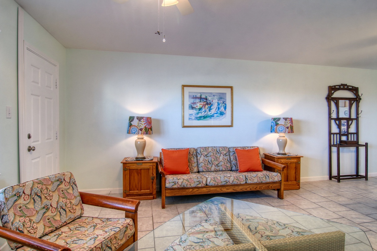 Unwind in your spacious living room featuring comfortable seating, tropical artwork, and warm island-inspired décor that invites relaxation.