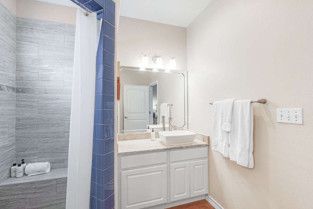 Your private bathroom features modern finishes with a glass shower, vanity with vessel sink, and fluffy towels for your comfort.