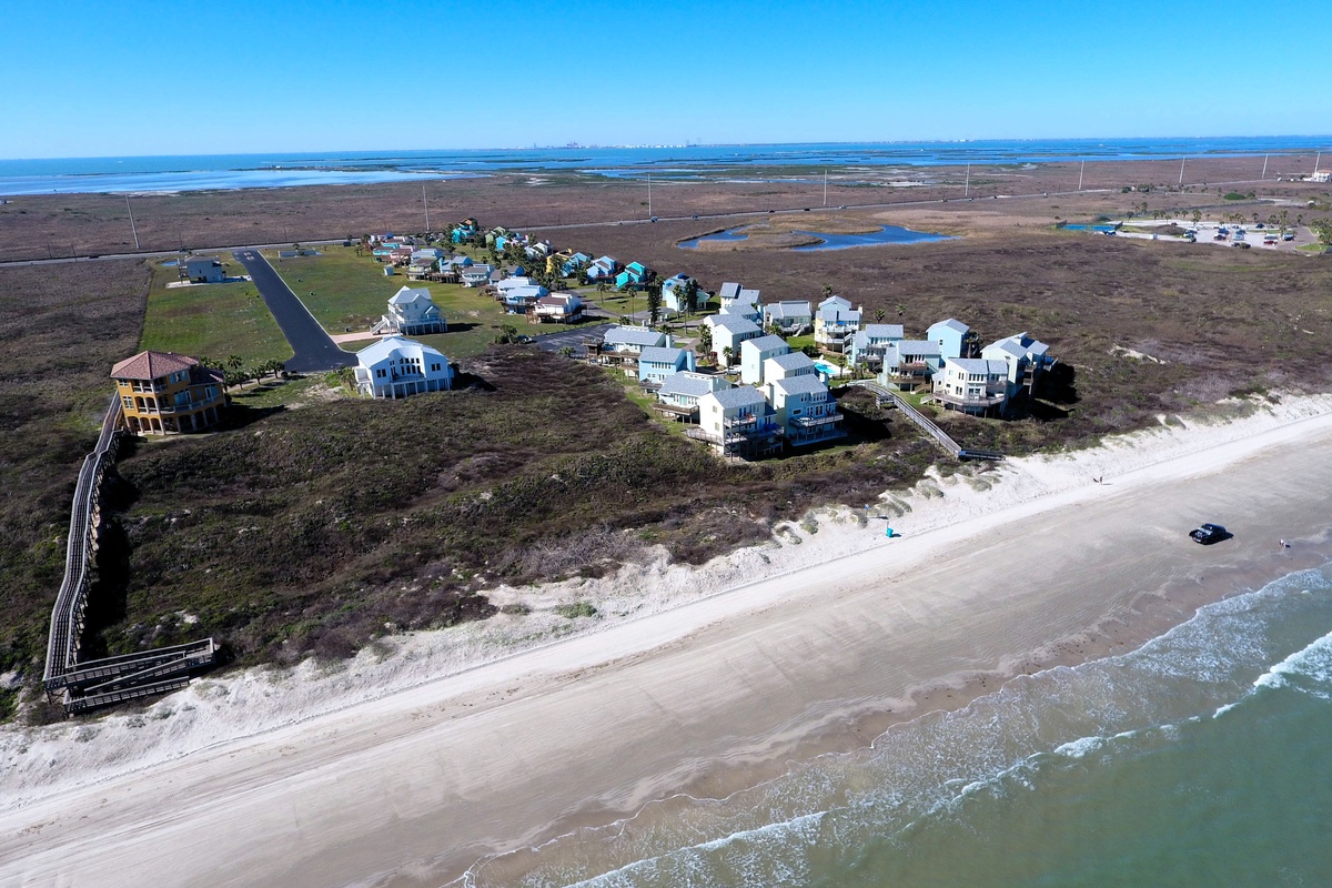 Aerial view of beachfront vacation rental community featuring direct beach access and coastal homes along pristine shoreline.