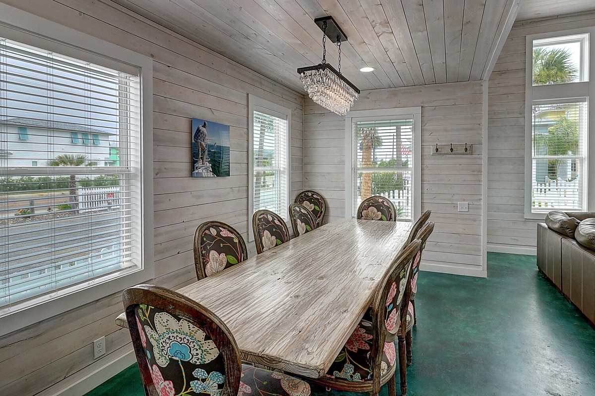 Gather around this gorgeous rustic dining table where your group can enjoy meals together under elegant chandelier lighting in this charming beachy space.