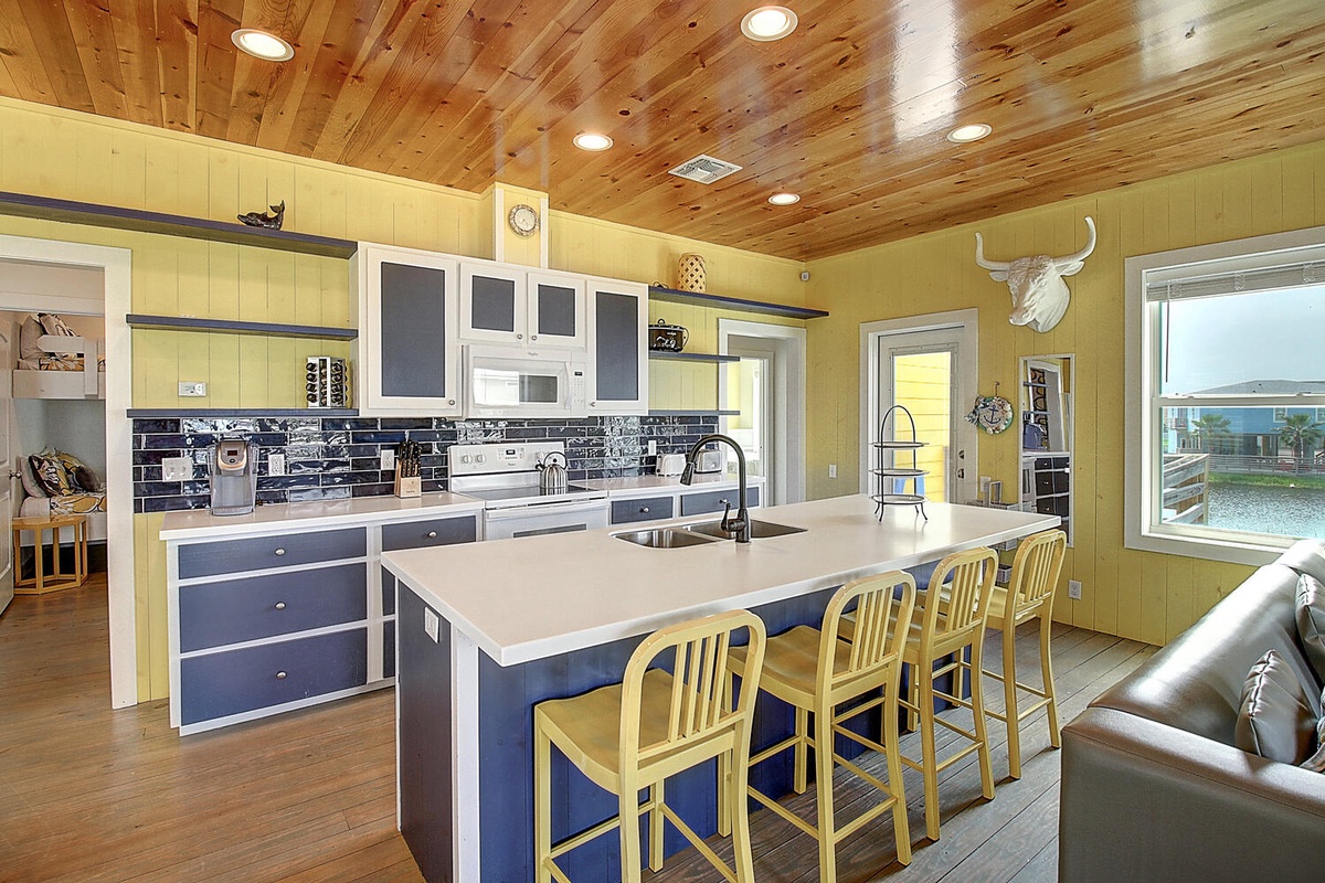 Your spacious kitchen invites culinary adventures with its rustic wood ceiling, sleek island seating for four, and modern appliances.