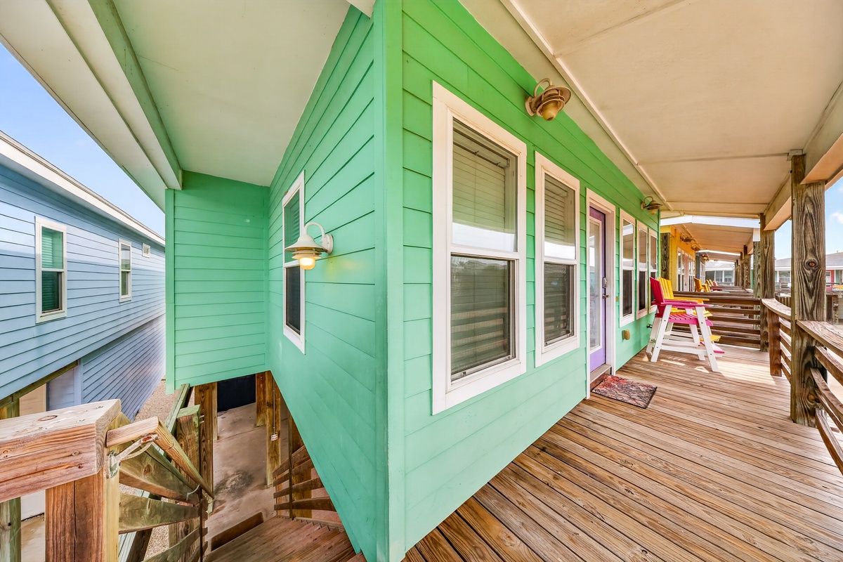 A bright turquoise exterior and spacious wooden deck set a cheerful, coastal tone. Natural light flows throughout, inviting you to enjoy breezy beach living in this vibrant retreat.