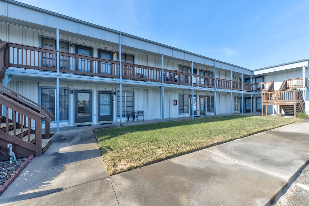 The property's exterior features a classic two-story design with private balconies and convenient ground-level access to numbered guest rooms.