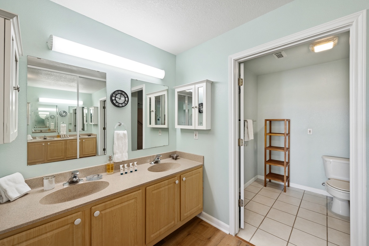 Step into your spacious bathroom with dual sinks, warm wood cabinetry, and calming coastal colors—perfect for getting ready in the morning or unwinding after a day at the beach.