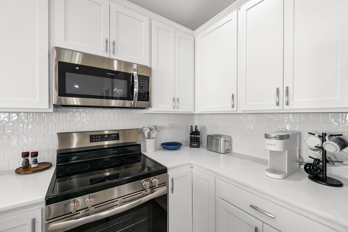 Your fully equipped kitchen awaits with gleaming stainless steel appliances and pristine white cabinetry, perfect for preparing memorable meals during your stay.