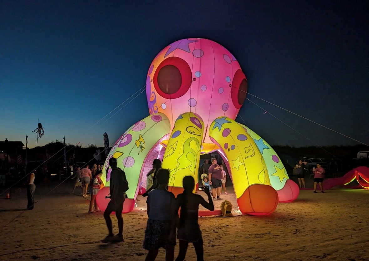 A whimsical giant octopus art installation lights up the evening sky, creating magical moments for families and festival-goers gathered nearby.