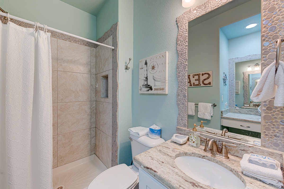 Your private bathroom offers a relaxing retreat with coastal touches, granite countertops, and a spacious walk-in shower for unwinding after beach days.