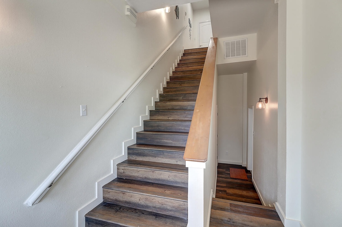 Your modern staircase features beautiful hardwood steps and clean white railings, creating an elegant pathway to your private upstairs retreat.