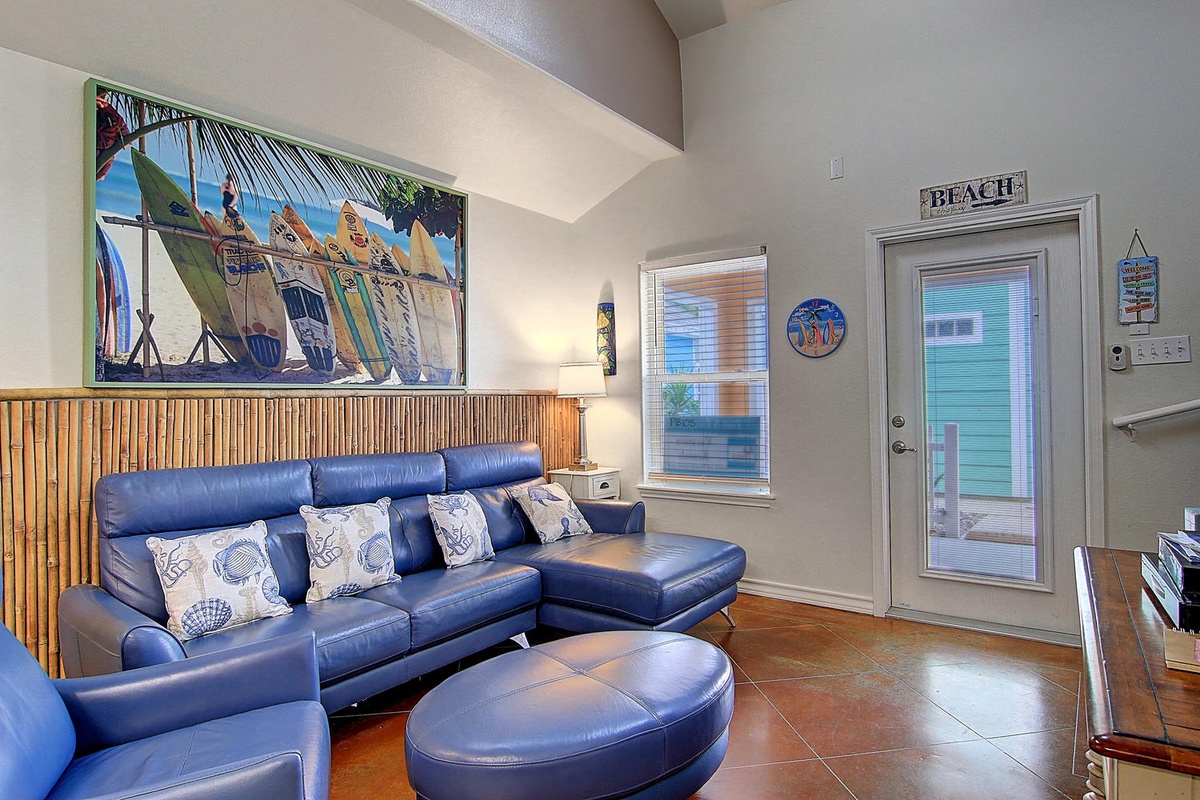 Sink into plush blue leather seating while beach art and bamboo accents transport you to coastal paradise in this bright, airy living space.