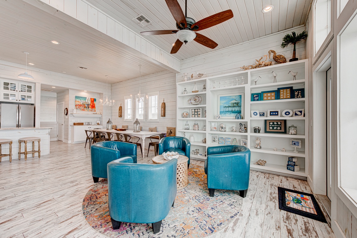 Sink into vibrant turquoise chairs while ocean treasures surround you in this coastal living space with soaring shiplap ceilings and beach-themed displays.