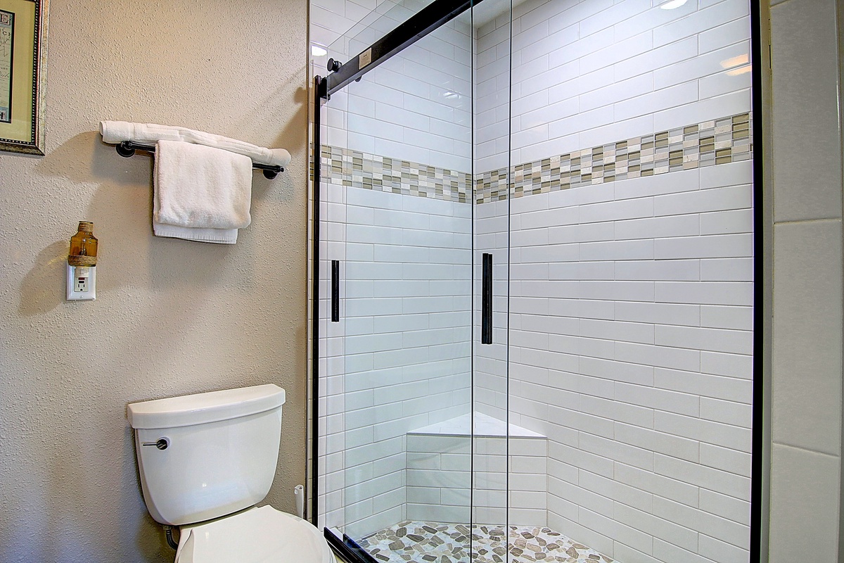 Step into your spa-like bathroom featuring a stunning glass-enclosed shower with elegant subway tiles and mosaic accents.