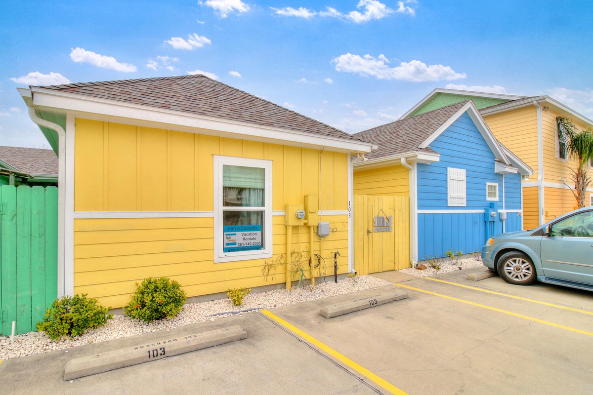 Cheerful beach-style cottages with vibrant yellow and blue exteriors create a welcoming coastal atmosphere with dedicated parking.