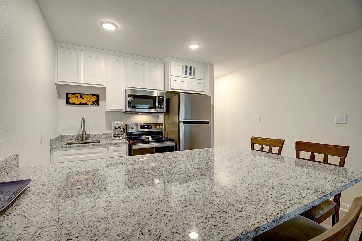 Cook your favorite meals in this bright, fully-equipped kitchen featuring granite countertops, stainless appliances, and comfortable seating for dining together.