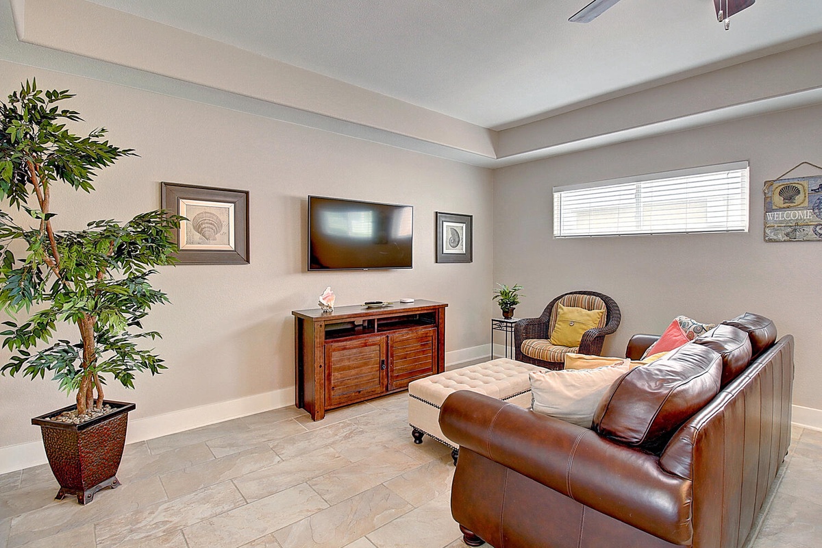 Settle into this comfortable living room with rich leather seating and modern entertainment setup for your perfect evening unwind.