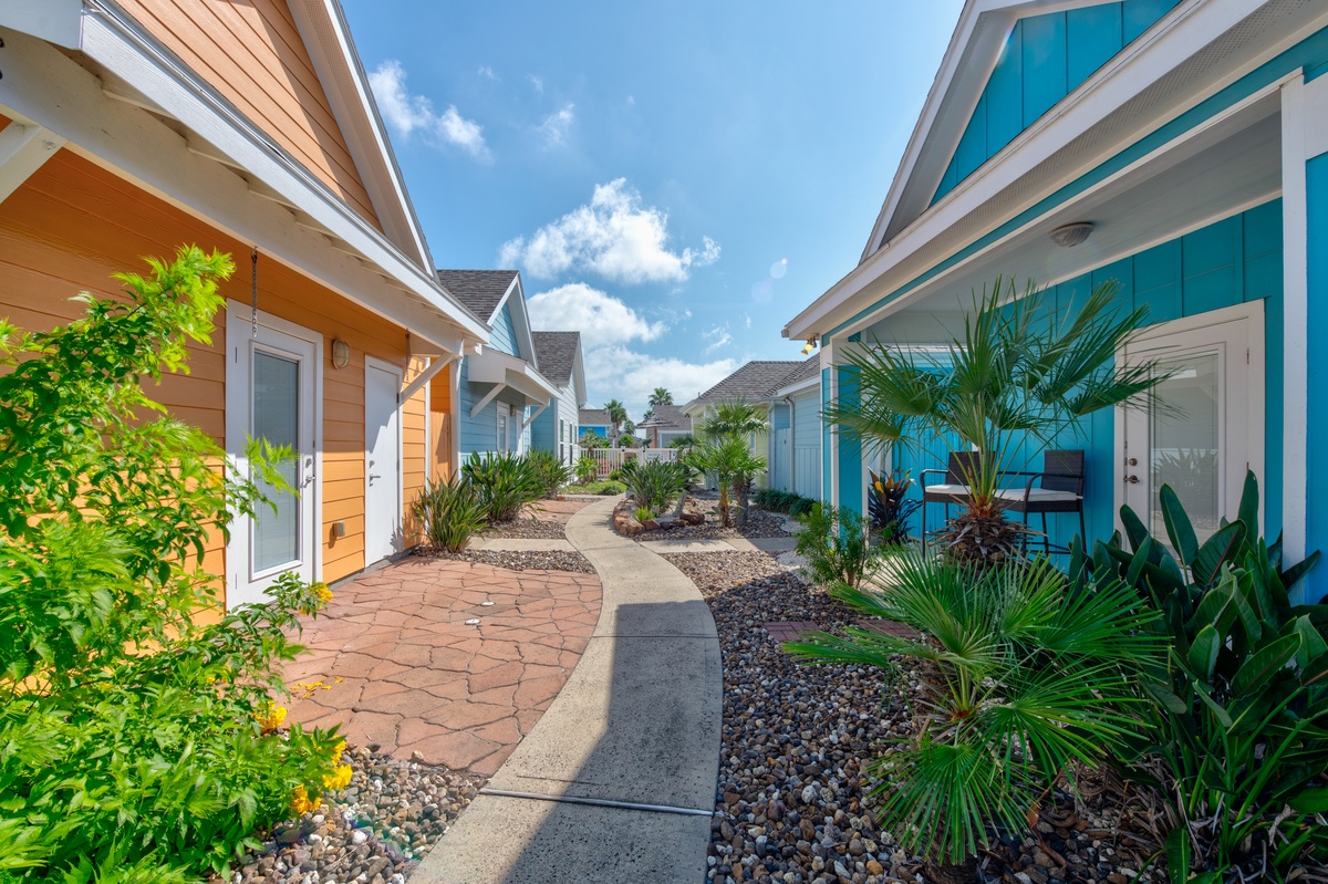 Vibrant tropical cottage community with colorful facades and lush landscaping under bright blue skies.