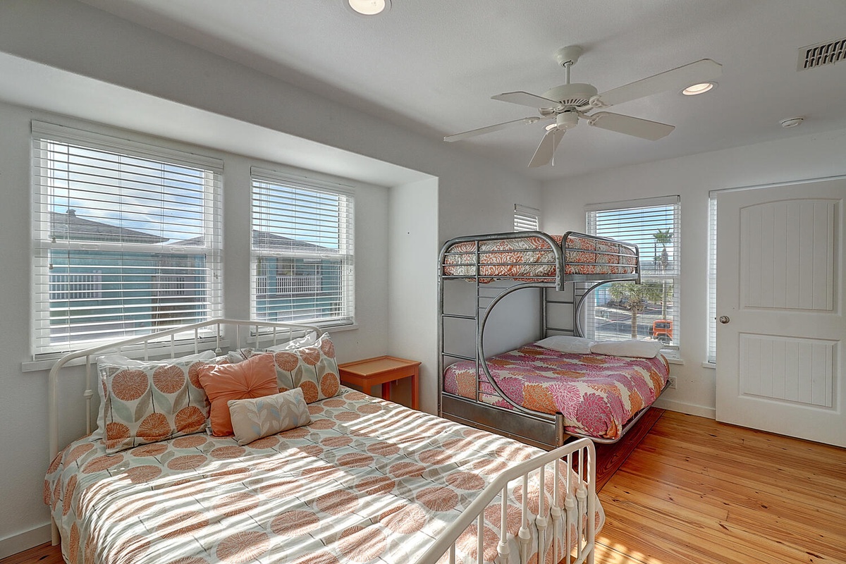 Your bright bedroom features colorful bedding and bunk beds, perfect for families. Natural light fills the space through large windows.