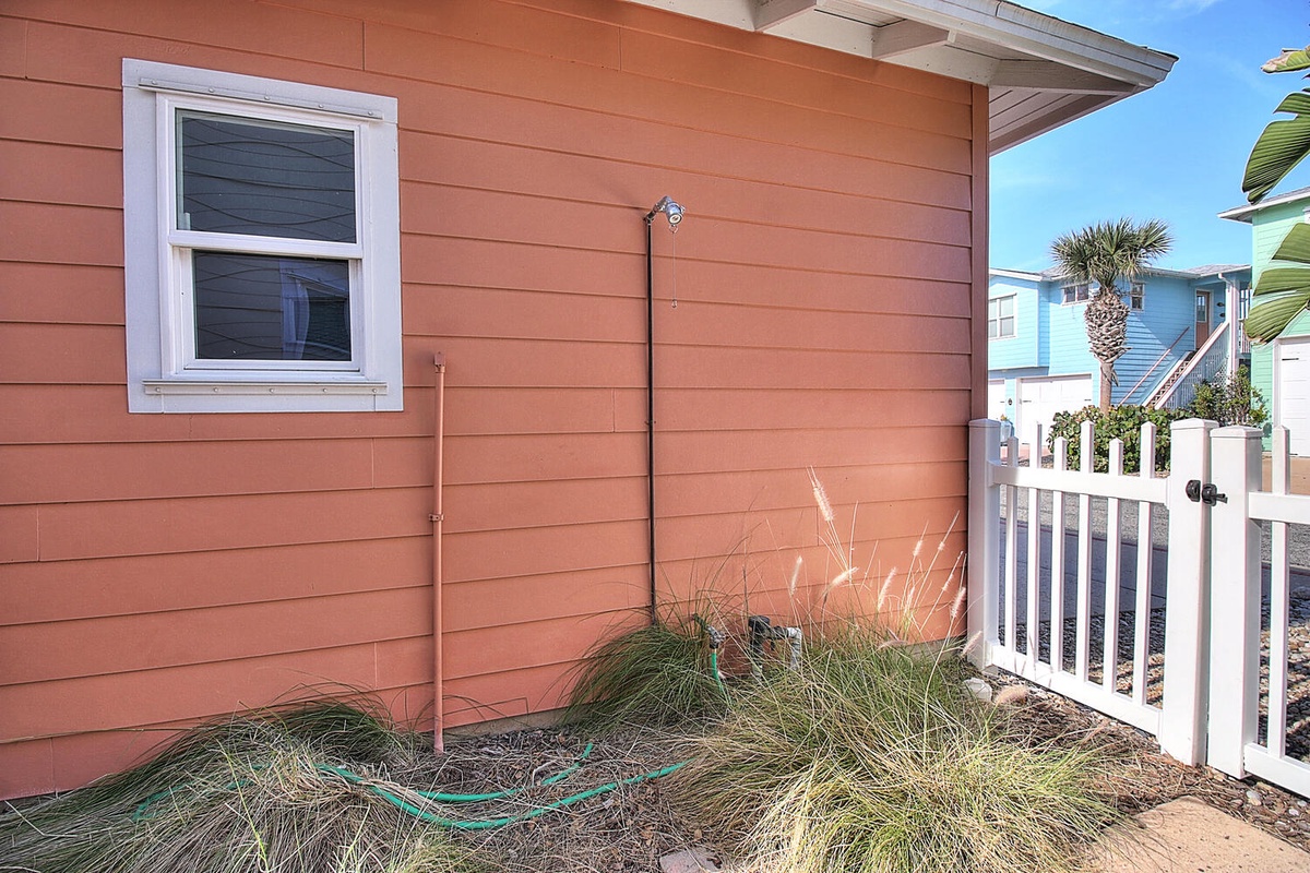 Charming coral-colored cottage exterior featuring bright tropical landscaping and classic coastal architecture in a peaceful residential setting.