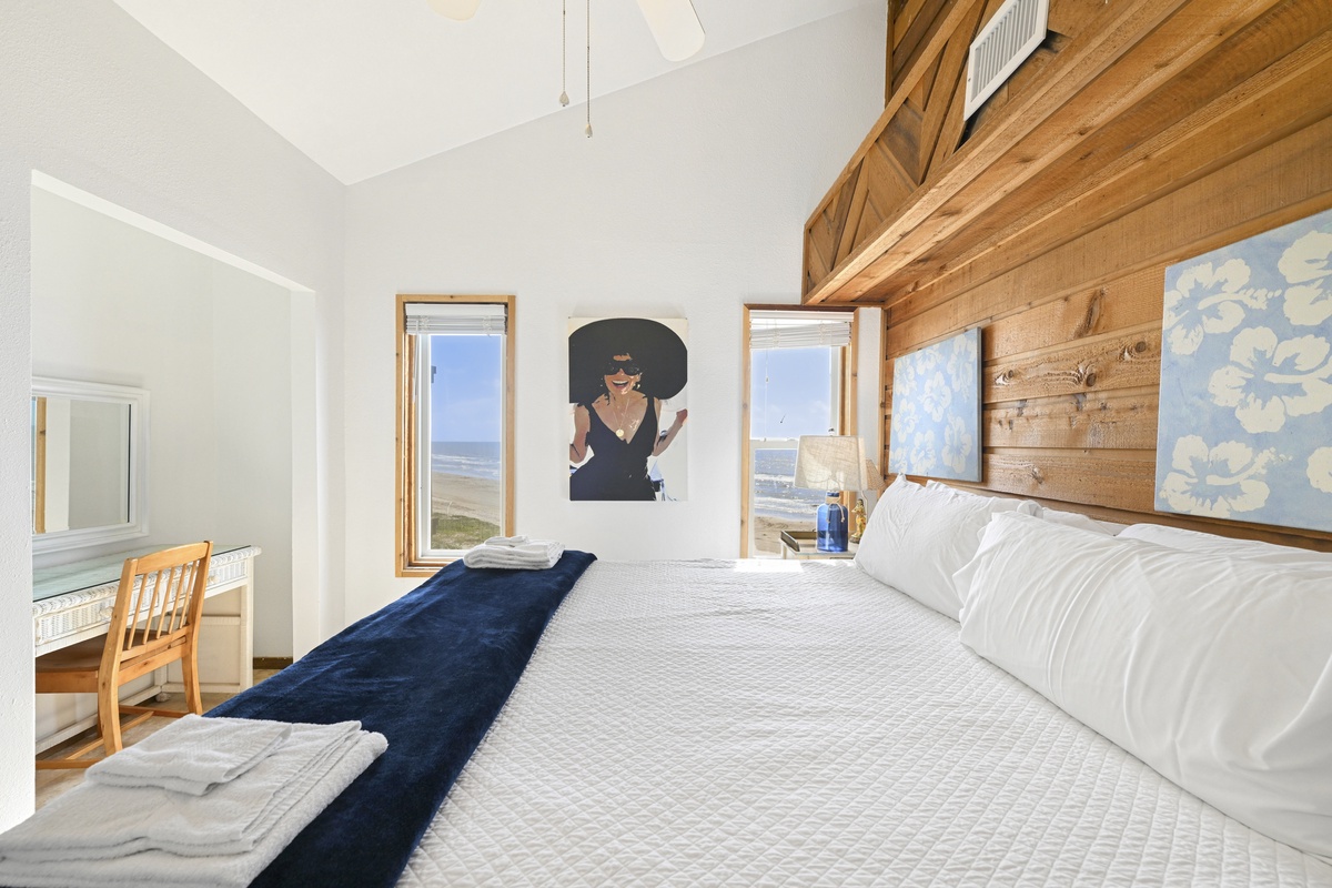 Wake to sunlight streaming through windows framing coastal views, with crisp linens inviting restful nights beneath soaring ceilings and warm wood accents that bring natural elegance to your seaside escape.