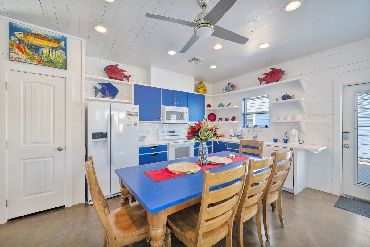 Your vibrant beach-themed kitchen invites you to cook with ocean-inspired blue cabinets, playful fish décor, and a sunny dining space perfect for shared meals.