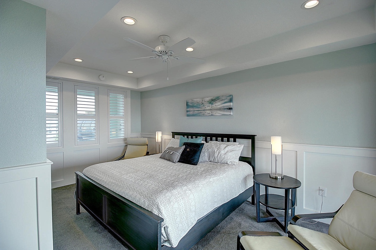Relax in your serene bedroom with soft blue walls, crisp white linens, and gentle natural light filtering through plantation shutters.