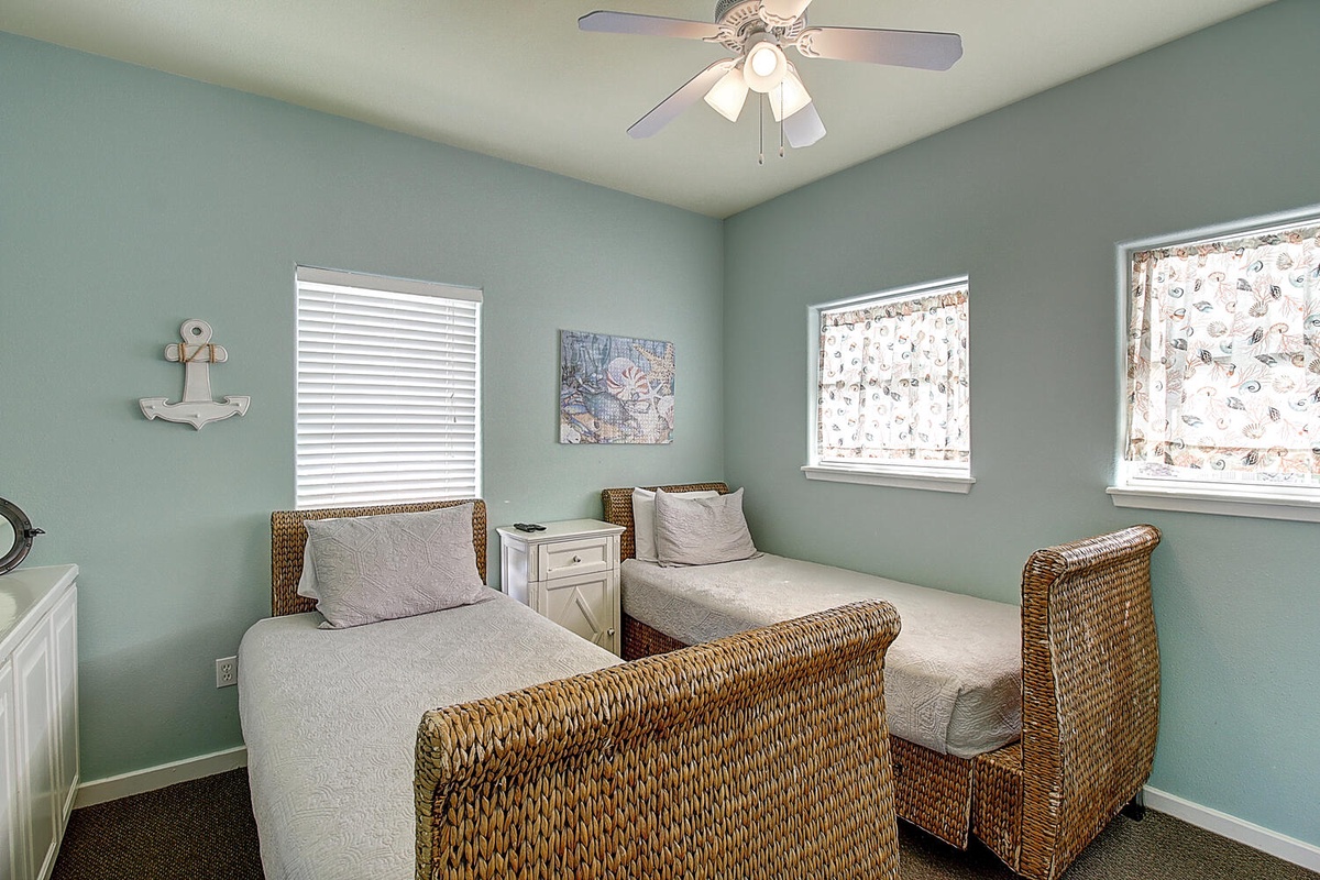 Your twin bedroom offers coastal charm with woven beds, soothing mint walls, and natural light for peaceful nights.