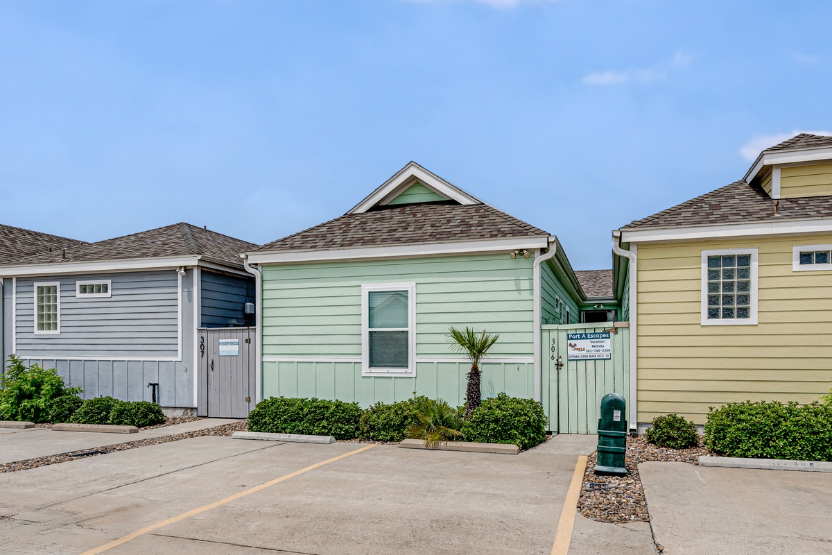 Charming coastal cottages with colorful siding and tropical landscaping create a welcoming beachside community atmosphere.