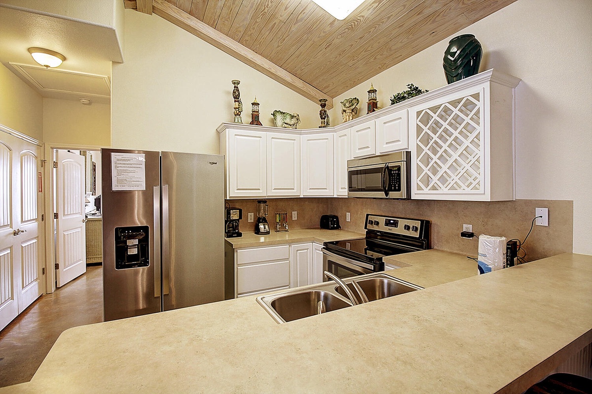 Your spacious kitchen features stainless steel appliances, granite countertops, and white cabinetry with charming wood plank ceilings overhead.