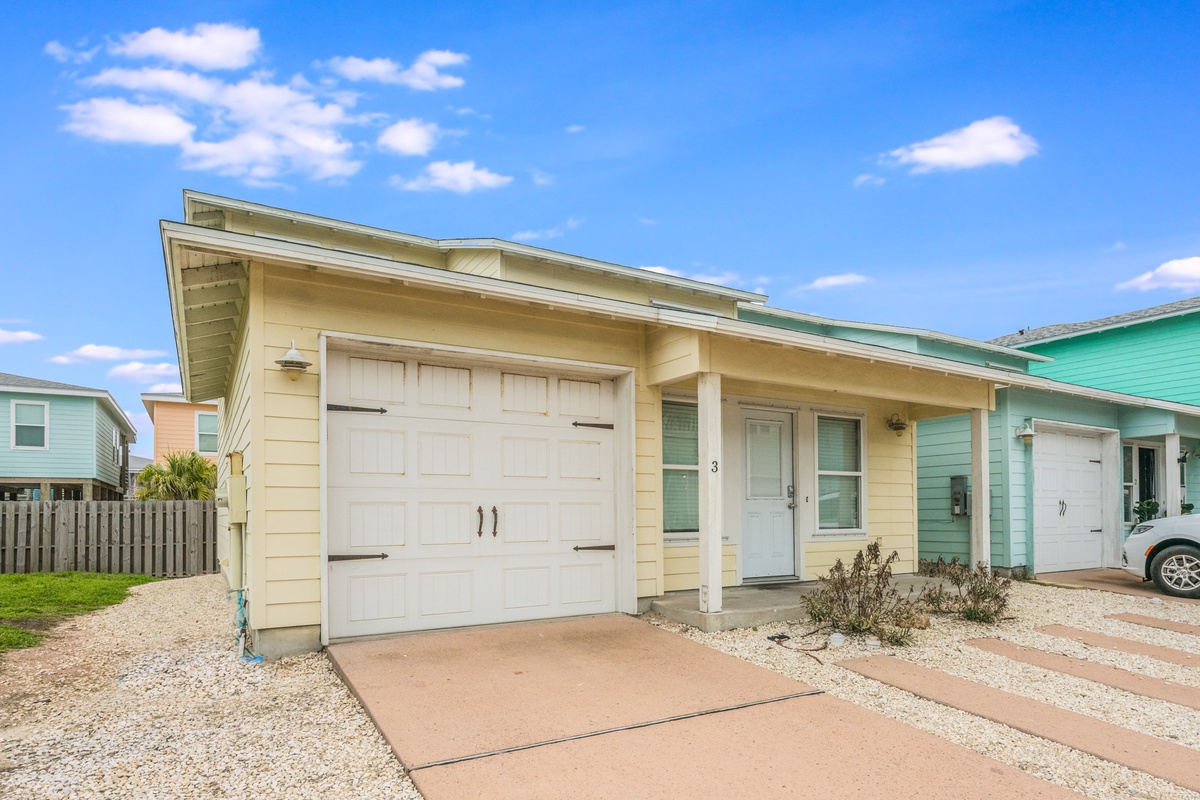 Charming beachside home with garage parking and coastal architecture in a colorful neighborhood setting.