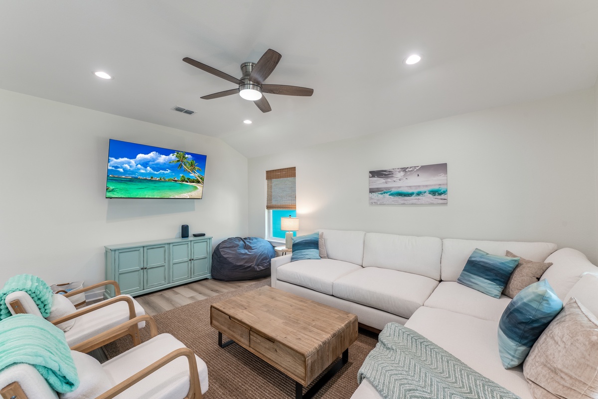 Unwind in your bright, coastal living room with plush sectional seating and tropical beach artwork that sets the perfect vacation mood.