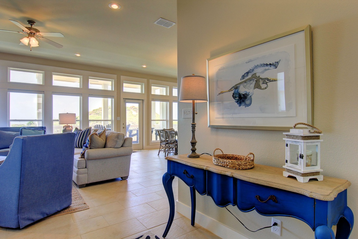Sink into plush sofas beneath soaring ceilings while natural light floods your bright, coastal-inspired living space.