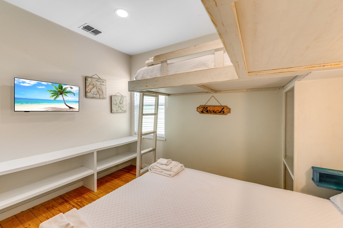 Your beach-themed bedroom features a cozy bunk bed setup with fresh linens and a mounted TV for relaxing after your adventures.