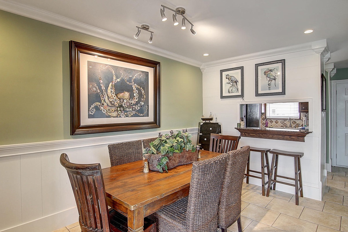 Gather around this warm dining space where ocean artwork and thoughtful lighting create the perfect atmosphere for your morning coffee or evening meals.